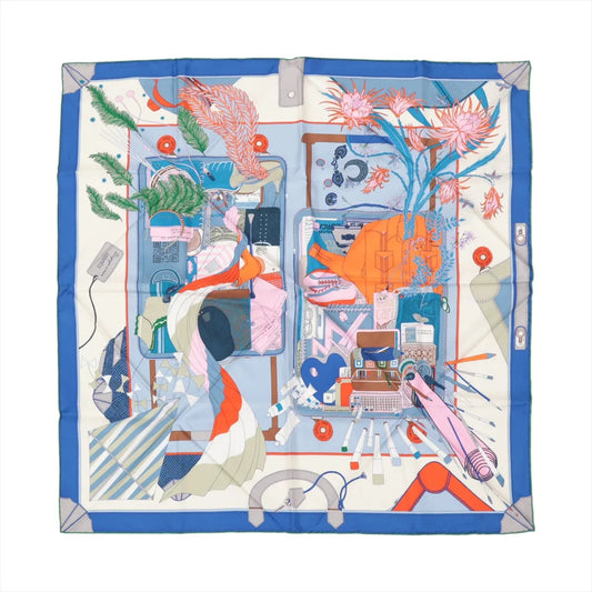 Hermès Carré 90 "Bagage à Main" silk scarf in blue featuring an illustrated scene of two open suitcases filled with clothes, flowers, books, shoes, and travel essentials, framed by a vibrant blue border.