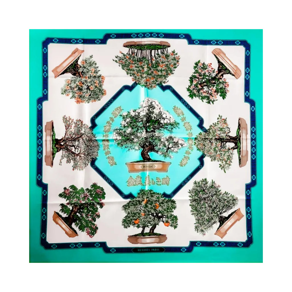 Hermès Bonsai square scarf laid flat, featuring potted flowering trees around a central bonsai, with turquoise panels, an ivory background and navy borders.