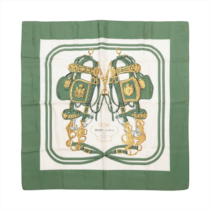 Hermès Carré 90 "Brides de Gala" silk scarf in green, featuring two ornate gold and green bridles mirrored at the center, framed by green borders and a white background with the title "Brides de Gala" in an elegant cartouche.