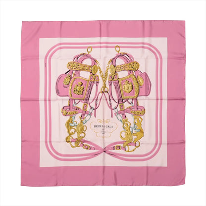 Hermès Carré 90 "Brides de Gala" silk scarf in pink featuring gold bridles and ornate equestrian harnesses on a pale background with pink borders.