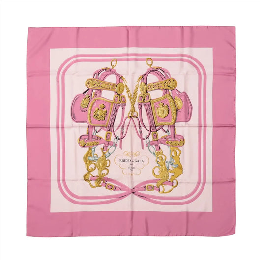 Hermès Carré 90 "Brides de Gala" silk scarf in pink featuring gold bridles and ornate equestrian harnesses on a pale background with pink borders.