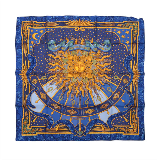 Hermès Carré 90 "CARPE DIEM" silk scarf in vibrant blue, featuring a radiant golden sun with a face at the center, surrounded by zodiac and celestial motifs, stars, moons, and Roman numerals on a detailed border.
