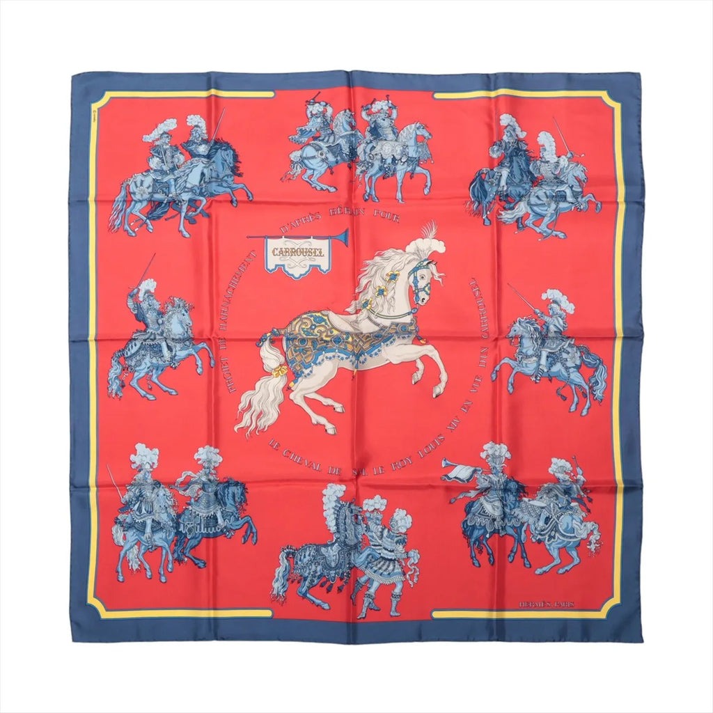 Hermès Carré 90 Carrousel silk scarf in red with a navy border, central white horse and blue ceremonial riders.
