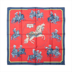 Hermès Carré 90 Carrousel silk scarf in red with a navy border, central white horse and blue ceremonial riders.