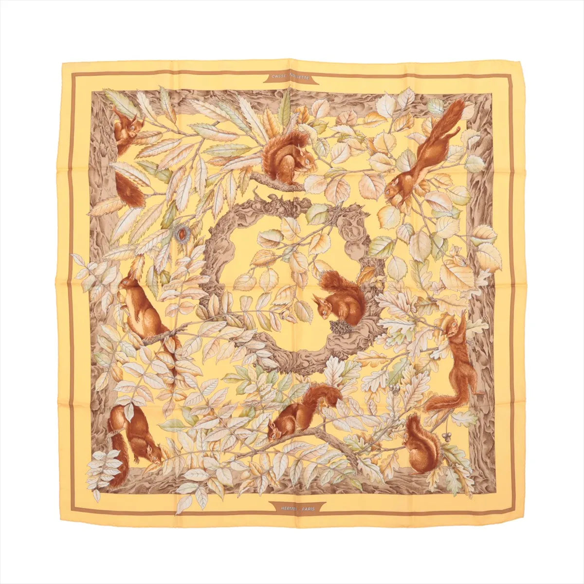 Hermès Carré 90 silk scarf titled "Casse Noisette," featuring detailed illustrations of brown squirrels playing among twisting branches and multicolored autumn leaves on a warm yellow background, bordered with golden and brown framing.