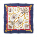 Hermès Carré 90 “Charreada” silk scarf with navy border, red frame, ivory center with rodeo rider scenes, and looping gold lariat motif.