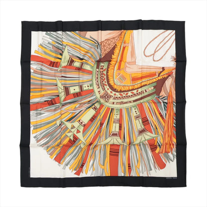 Hermès Carré 90 "Cuirs du Désert" silk scarf in black and orange featuring a close-up of an abstract desert saddle motif with multicolored fringe in orange, yellow, green, and grey tones, bordered in black.