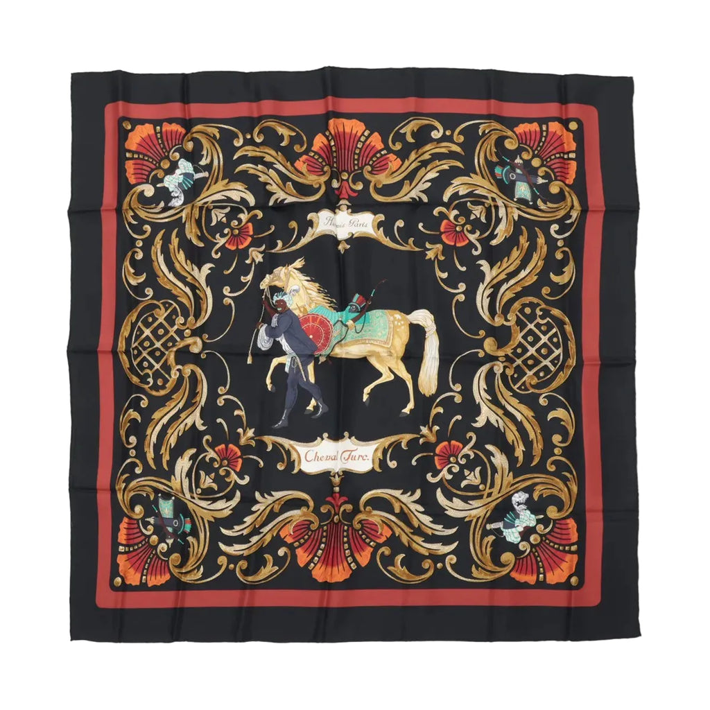 Hermès Carré 90 “Cheval Turc” silk scarf in black with red border, ornate gold scrollwork frame, and central horse and figure illustration.