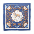 Flat-lay of a Hermès Carré 90 "Cheval Turc" silk scarf in blue featuring a central illustration of a Turkish horse and rider, surrounded by intricate baroque scrollwork and ornamental flourishes in gold, blue, and white tones.
