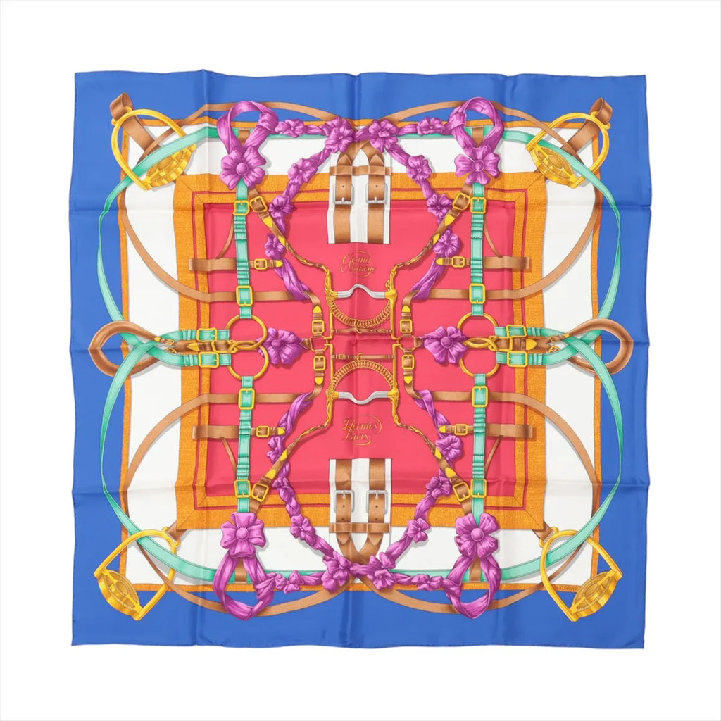 Hermès Carré 90 silk scarf in blue with red center panel, featuring gold harness and buckle motifs, teal straps, and purple ribbon flowers.