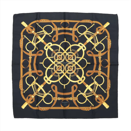 Hermès Carré 90 silk scarf titled "Éperon d'Or," showcasing an intricate pattern of golden stirrups, reins, and leather harnesses arranged in a symmetrical, circular layout on a rich black background, blending equestrian tradition with luxurious detail.
