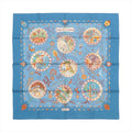 Blue Hermès Carré 90 silk scarf laid flat with multicolor Mediterranean-themed illustration in circular vignettes and a decorative border on a white background.