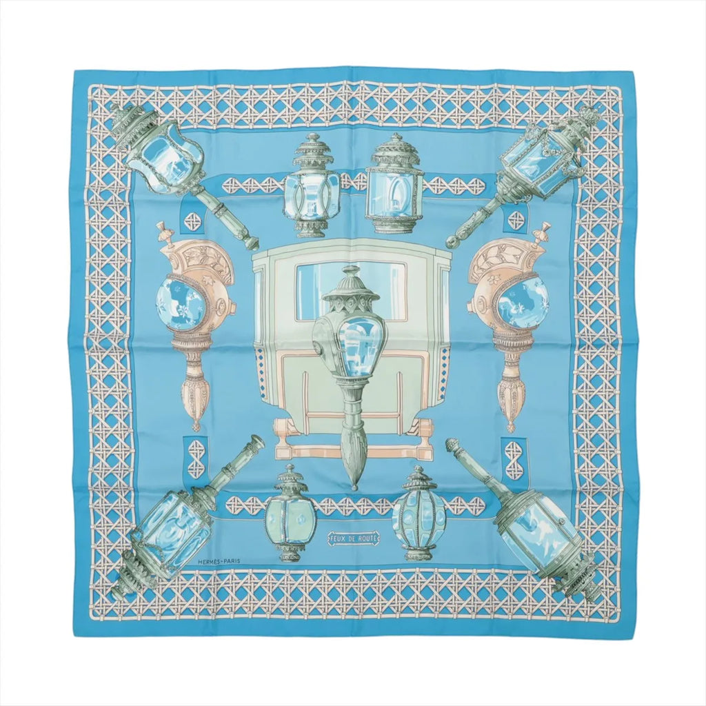 Hermès Carré 90 "FEUX DE ROUTE" silk scarf in blue with ornate carriage lanterns, a vintage coach, and a geometric border.