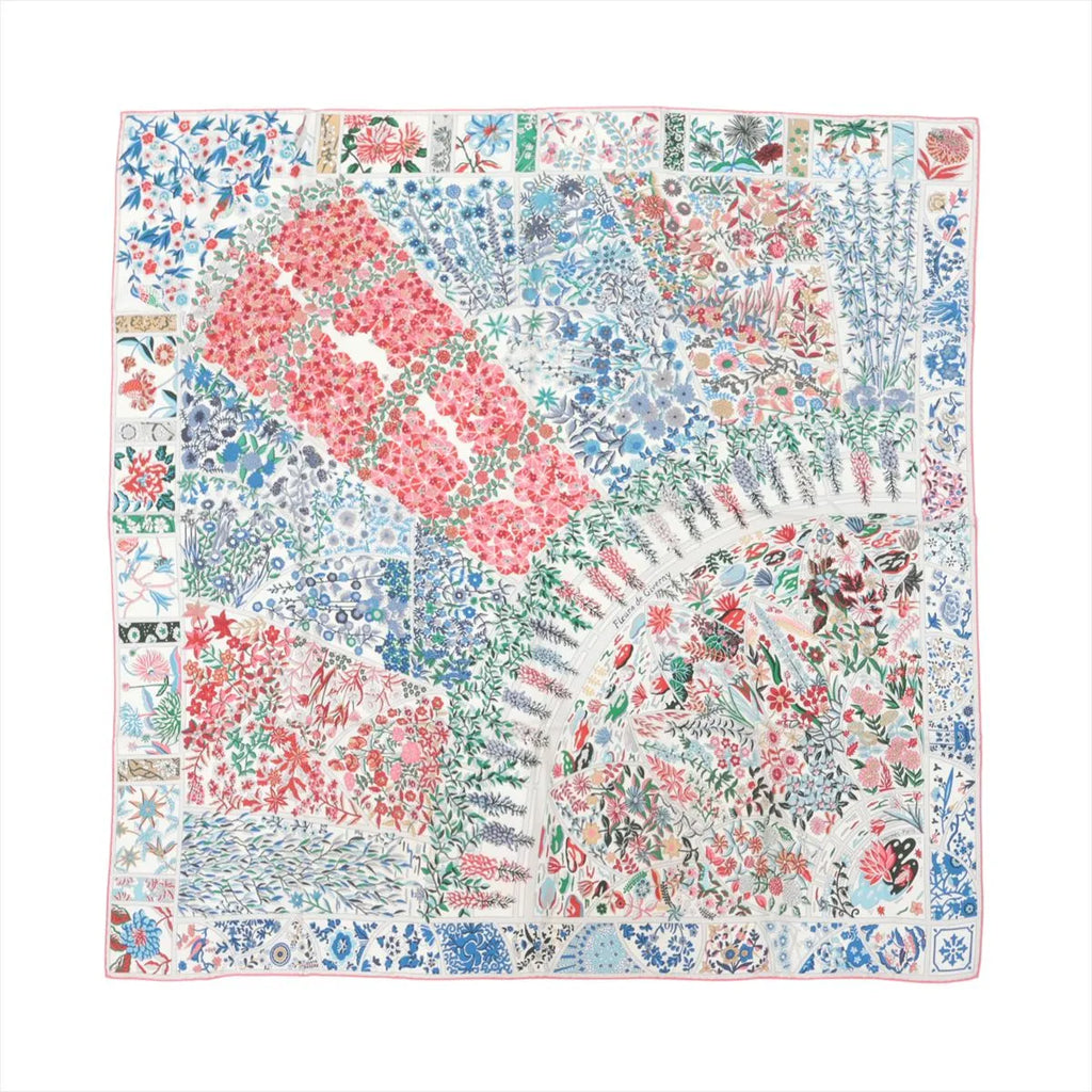 Hermès Carré 90 silk scarf with multicolor floral patchwork design in red, blue, green, and gray tones, finished with a thin pink border on white background