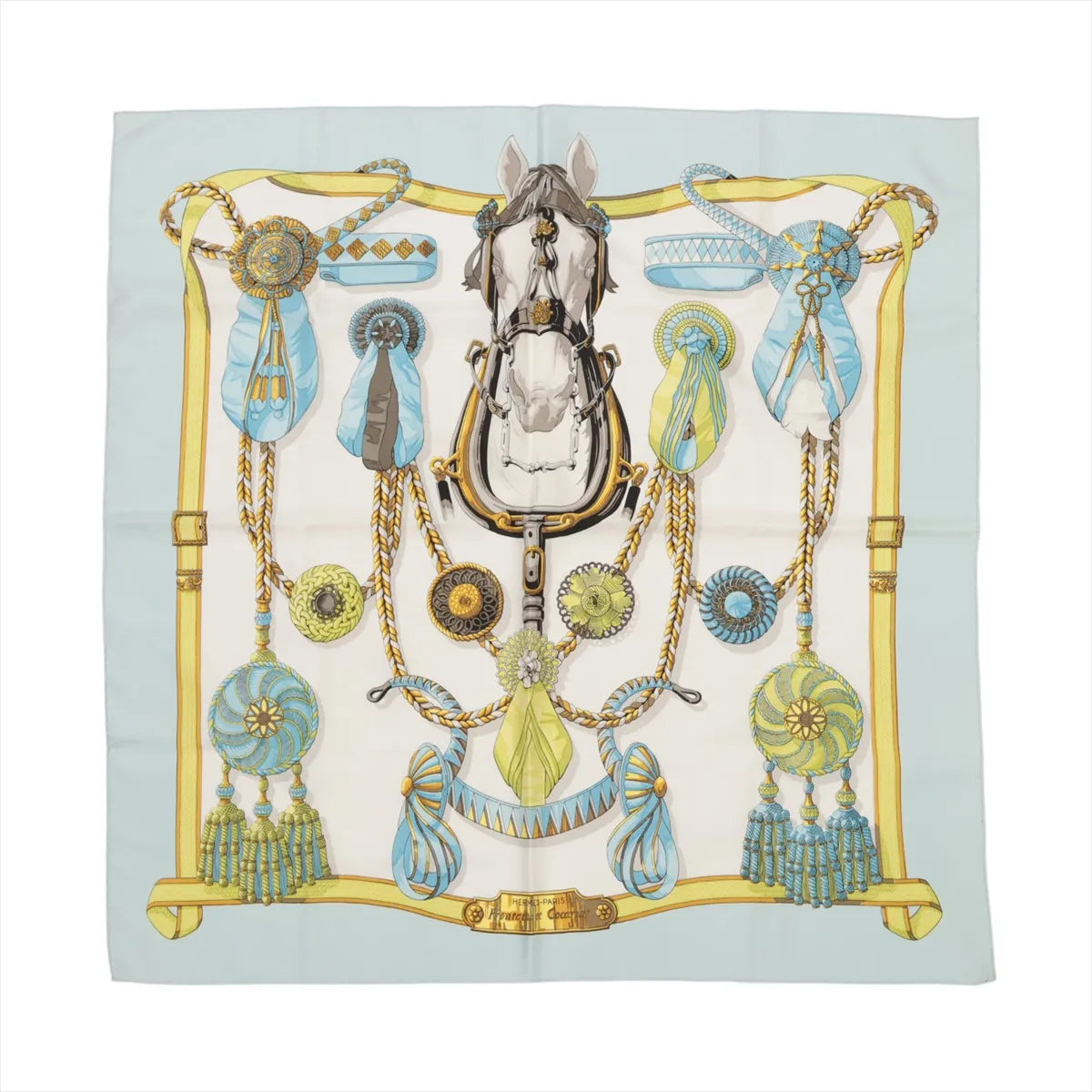 Hermès Carré 90 silk scarf in light blue featuring a central horse head surrounded by bridles, rosettes, and cockades in gold, blue, and green accents.