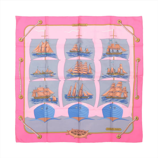 Hermès Carré 90 "GRAND LARGUE" silk scarf in pink featuring illustrations of vintage sailing ships on blue seas, arranged in a grid with nautical rope border and ship wheel detail at the bottom.