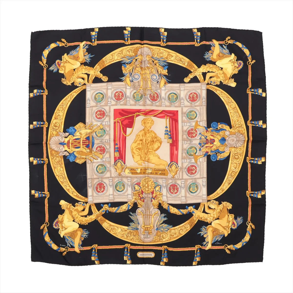 Hermès Carré 90 silk scarf titled "Hommage à Charles Garnier," featuring an ornate tribute to the Paris Opera architect with gold scrollwork, classical figures, and medallions surrounding a central statue, set on a black background with red and blue accents.