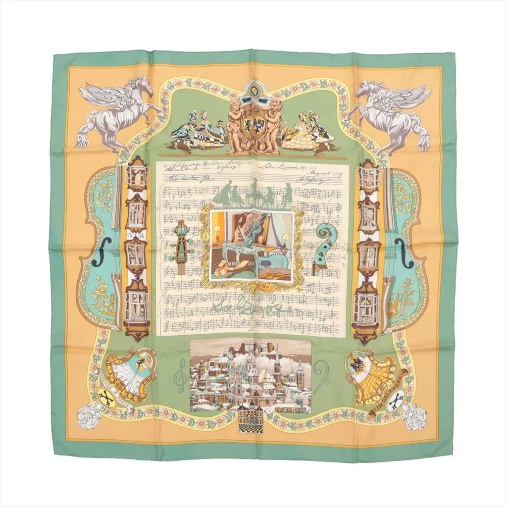 Hermès Carré 90 silk scarf titled "In Salzburg," featuring a central musical score with baroque illustrations, dancers, cherubs, and classical motifs, framed by green and golden yellow borders with scenes of Salzburg architecture and whimsical details.