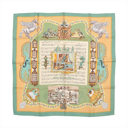 Hermès Carré 90 silk scarf titled "In Salzburg," featuring a central musical score with baroque illustrations, dancers, cherubs, and classical motifs, framed by green and golden yellow borders with scenes of Salzburg architecture and whimsical details.