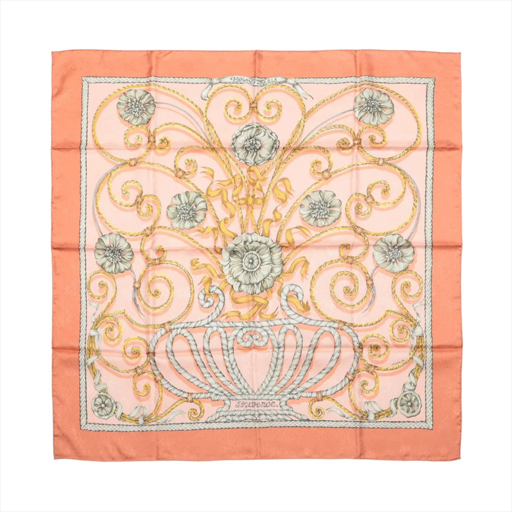 Hermès Carré 90 silk scarf in orange with pink center, gold scrollwork and floral motif, and orange border, laid flat
