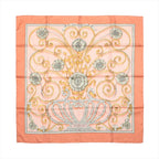 Hermès Carré 90 silk scarf in orange with pink center, gold scrollwork and floral motif, and orange border, laid flat