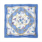 Hermès Carré 90 blue silk scarf with flying birds in blue and pink, ornate gold scrollwork circles, and a blue border with patterned corner details.