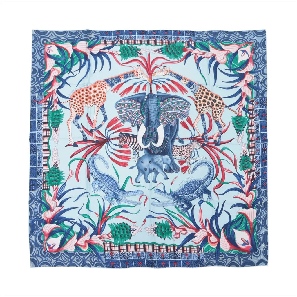 Hermès Carré 90 blue silk scarf with central elephant, giraffes, crocodiles, zebra, floral border, and multicolor wildlife motif on white background