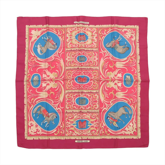 Hermès Carré 90 silk scarf in burgundy with a symmetrical layout of ornate gold scrolls, blue and red equestrian vignettes, and horses with riders on a rich silk twill.