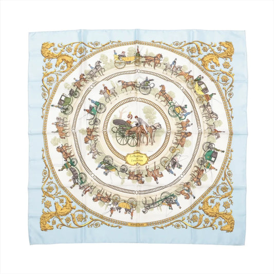 Hermès Carré 90 "La Promenade de Longchamps" silk scarf in light blue, showcasing concentric circles of detailed horse-drawn carriages, riders, and gold ornamental corner accents.