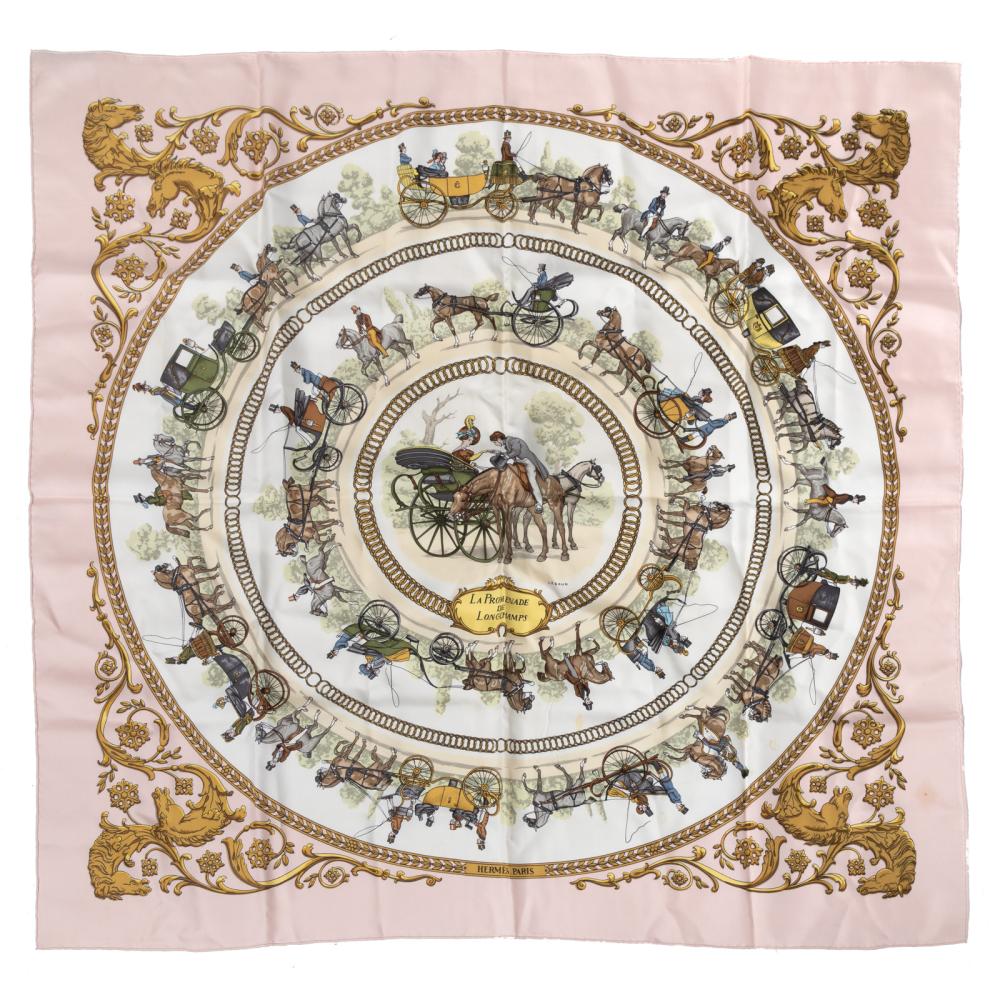The Hermès Carré 90 “La Promenade de Longchamps” silk scarf in pink showcases an elegant equestrian carriage motif framed by ornate golden scrollwork. Luxurious and timeless, it’s perfect for collectors and style enthusiasts.