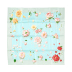 Hermès Carré 90 La Rosée silk scarf in pale blue with pink, yellow, and red rose print, scattered petals, light green border, and visible fold lines on white background.