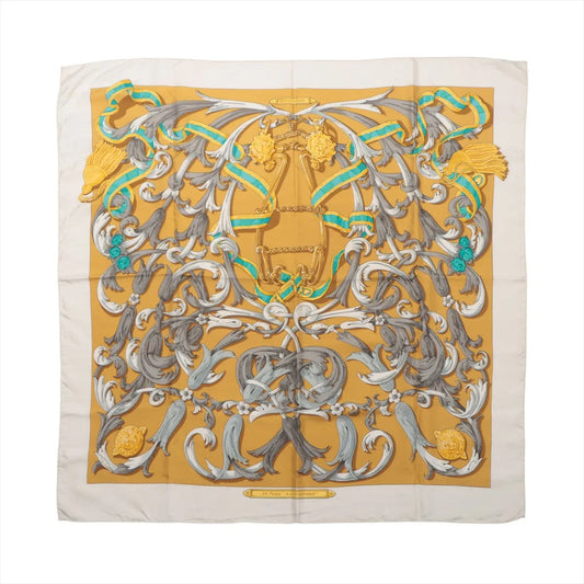 Hermès Carré 90 "Le Mors à la Conétable" silk scarf in yellow with elaborate equestrian bridle motif in gray, white, gold, and green, framed by a cream border.
