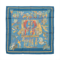 Hermès Carré 90 blue silk scarf with marionette theatre illustration, figures around a central stage scene, and yellow border accents