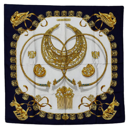Hermès Carré 90 “Les Cavaliers d'Or” silk scarf in navy blue with a central gold motif of intertwined horse-themed ornaments, medallions, and regal details on a white background.