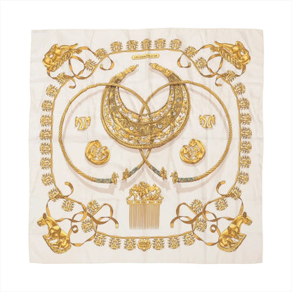 Hermès Carré 90 "LES CAVALIERS D'OR" silk scarf in white, featuring intricate gold illustrations of horse-themed jewelry, including medallions, combs, and collars, arranged symmetrically with rope-like borders and ornate ribbon accents.