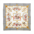 Gray Hermès Carré 90 silk scarf with ornate gold framing, horse and rider scenes, and ivory, red and blue accents.