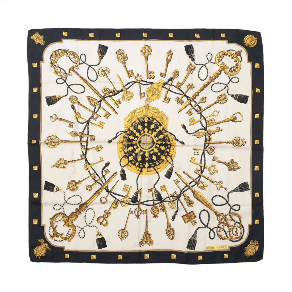 Hermès Carré 90 silk scarf in black and cream featuring ornate gold keys, black tassel cords and a decorative central medallion.