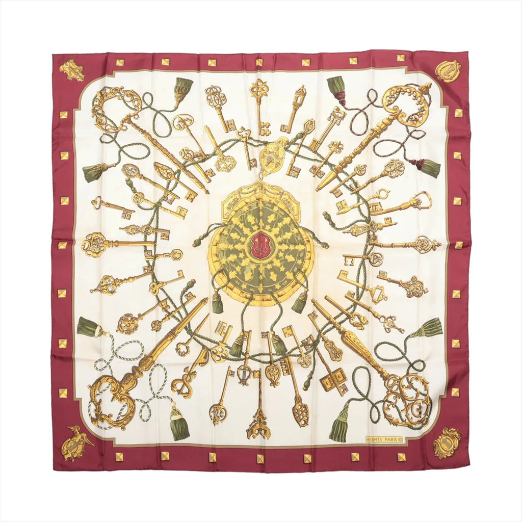 Hermès Carré 90 burgundy and ivory silk scarf with ornate gold key motifs, green tassels, a central circular medallion and burgundy border.