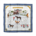 Hermès Carré 90 silk scarf in blue with an equestrian-themed design showing horses, riders, and a grand French estate in detailed illustrations.