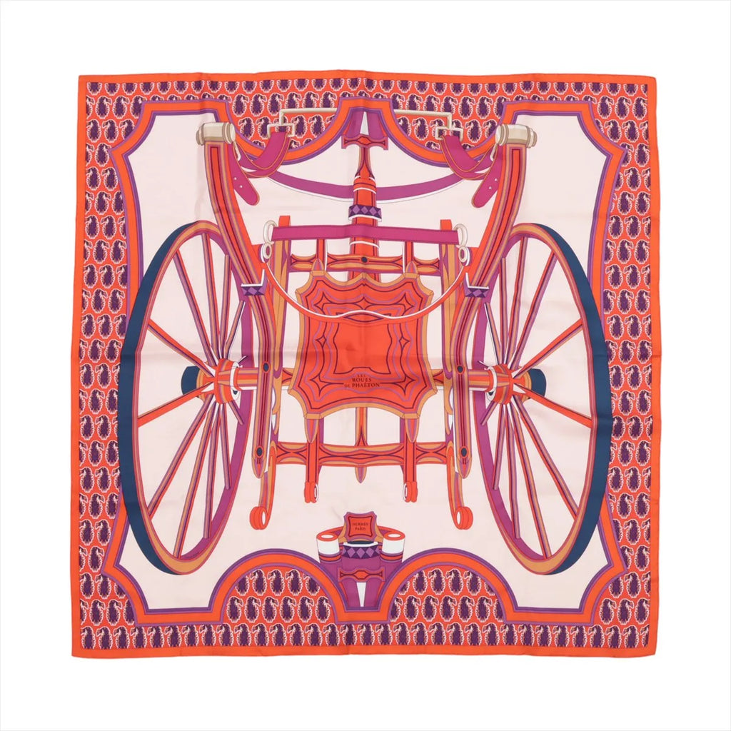 Hermès Carré 90 silk scarf in orange with a bold design of a decorative horse-drawn carriage and large wheels in pink, red, and purple on a light background.