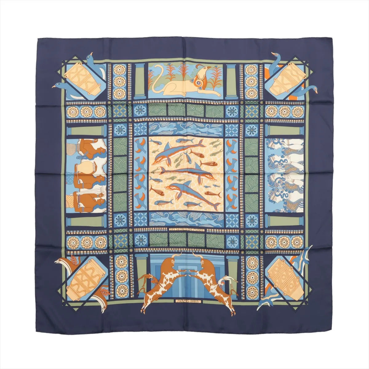 Hermès Carré 90 "Les Secrets de Minos" silk scarf in navy blue featuring a central motif of dolphins and fish, surrounded by panels depicting bulls, ancient columns, geometric patterns, and mythological elements in shades of blue, orange, cream, and green.