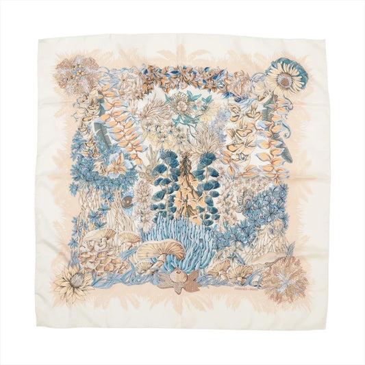 Hermès Carré 90 "L'Île Déserte" silk scarf featuring beige and blue botanical illustrations of flowers, leaves, and mushrooms on a cream background.