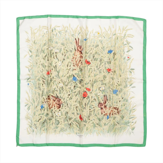 Hermès Carré 90 "Lapins Dans un Champ de Blé" silk handkerchief featuring detailed illustrations of rabbits hiding in a golden wheat field with red poppies and blue wildflowers, framed by a green border, laid flat against a white background.