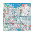 Hermès Carré 90 "Le Grand Prix du Faubourg" silk scarf in blue featuring a highly detailed and colorful Parisian cityscape with bustling crowds, storefronts, race cars, balloons, and whimsical illustrations.