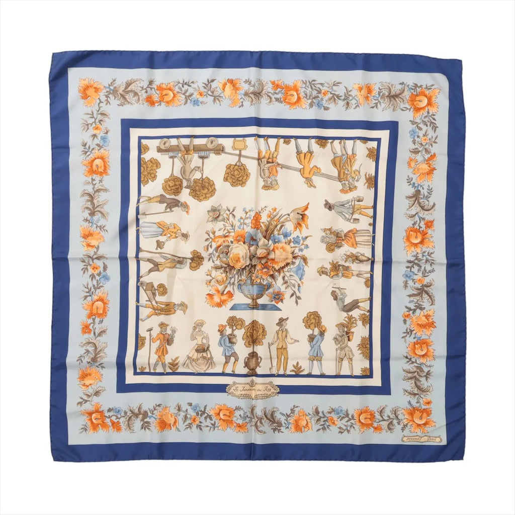 Blue Hermès Carré 90 silk scarf with orange floral border, illustrated garden figures and a large central flower arrangement.