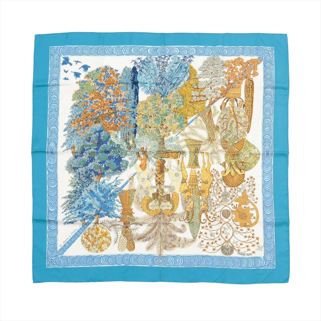Hermès Carré 90 blue silk scarf with “Les Légendes de L’Arbre” botanical tree illustration in blue, gold, and cream, framed by a solid blue border and patterned inner border.