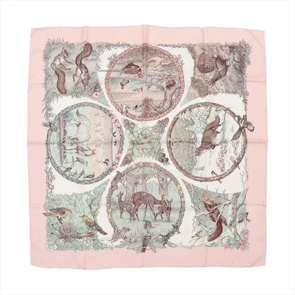 Hermès Carré 90 "Les Quatre Saisons" silk handkerchief in soft pink, featuring intricately illustrated woodland animals and seasonal nature scenes within circular frames, bordered by florals and delicate forest details on a cream background.