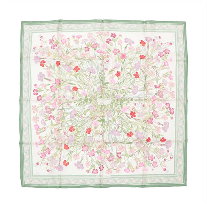 Hermès Carré 90 silk scarf featuring a detailed wild carnation floral design in shades of pink, red, and lilac on a white background, framed by a green and pastel pink border.