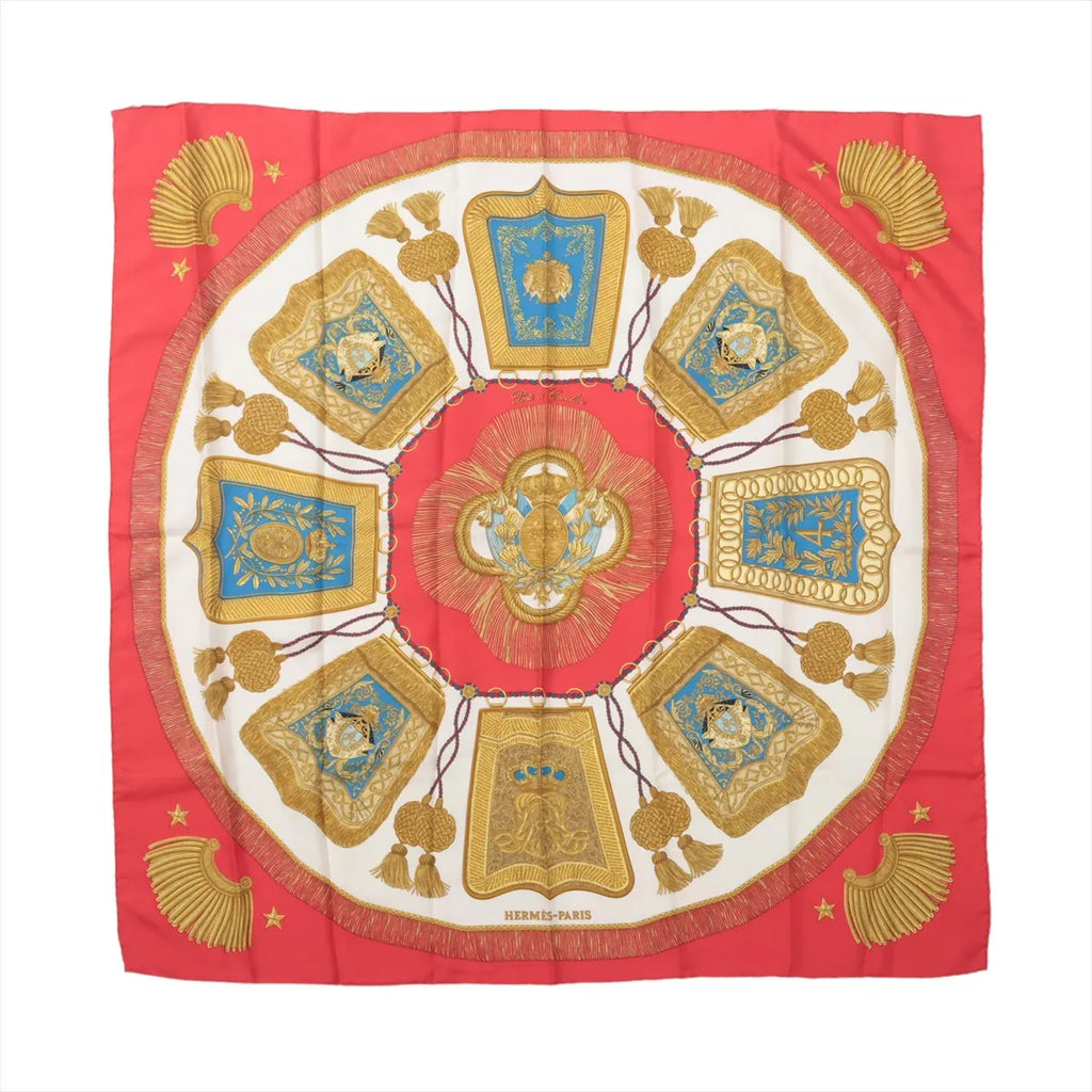 Red Hermès Carré 90 silk scarf with ivory center, turquoise panels and symmetrical gold cavalry-inspired ornaments, tassels and decorative motifs.
