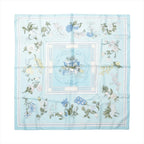 Hermès Carré 90 light blue silk scarf with white, blue and yellow flowers, green leaves and a horse-drawn flower cart at the centre.